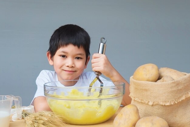 マッシュポテトを楽しく作る7歳の少年