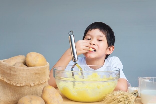 7 years boy making mashed potatoes happily