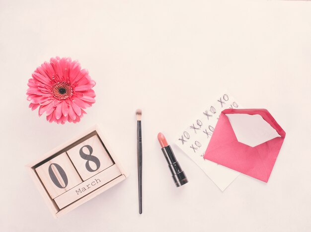 8 March inscription on wooden blocks with flower and lipstick on table 