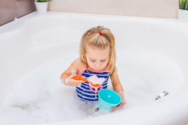 美しい浴室で泡風呂に入っている面白い小さなブロンドの女の子 子供の衛生 子供用のシャンプー ヘアトリートメント 石鹸 プレミアム写真