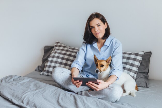 寝室で彼女の犬と一緒にポーズを取るハッピーティーンエイジャー 無料の写真