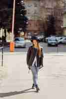 Бесплатное фото Молодая красивая девушка ходит по городу, улыбаясь и позирует