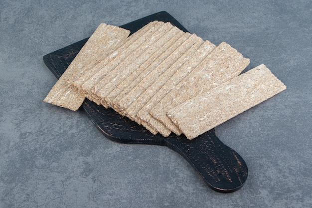 Бесплатное фото Черная деревянная доска, полная хрустящего хлеба.