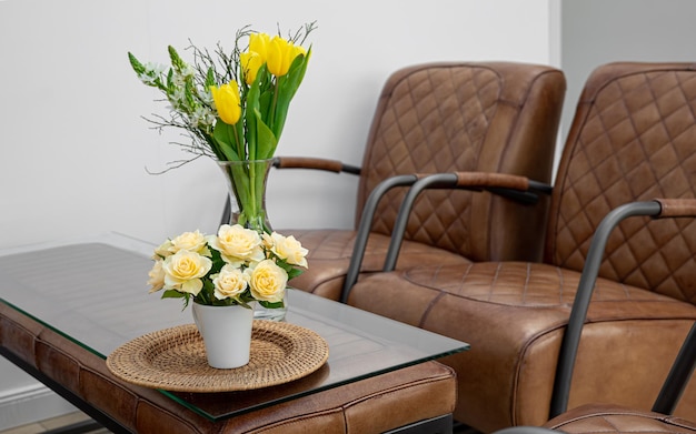 Бесплатное фото Букет цветов на столе в интерьере с кожаными креслами