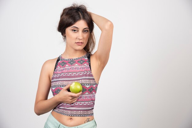 Очаровательная молодая женщина держит зеленое свежее яблоко.