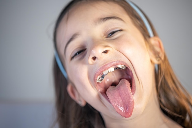 무료 사진 어린 소녀가 입을 벌리고 혀를 보여줍니다.