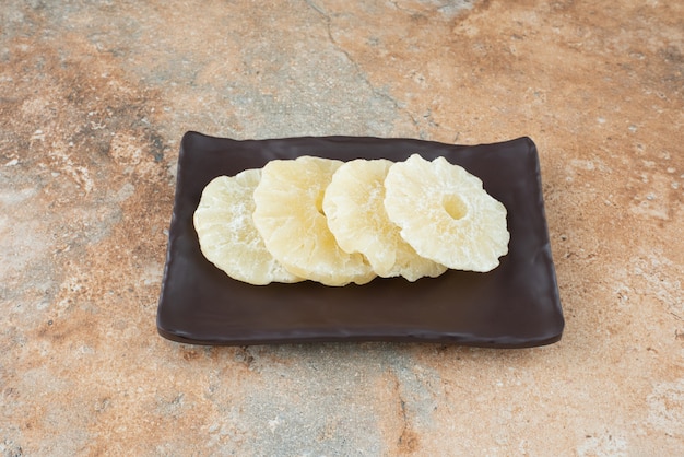 乾燥した健康的なパイナップルでいっぱいの暗いプレート 無料写真