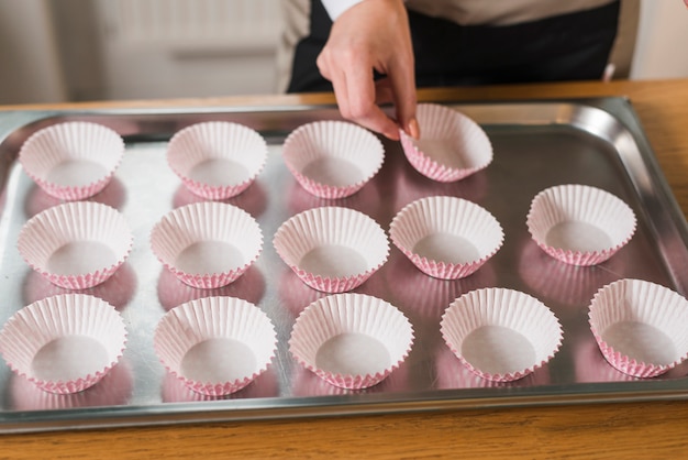 無料写真 ステンレス鋼の皿にカップケーキラッパーを配置する女性の手