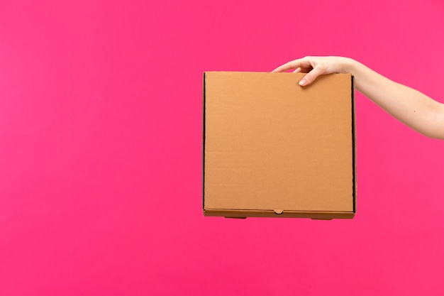 Бесплатное фото Вид спереди коричневая коробка рука коричневая коробка женская рука розовый цвет фона пищевой пакет