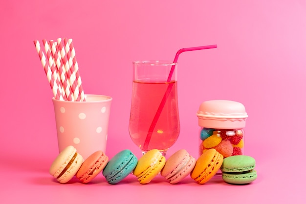 無料写真 正面のフレンチマカロンとフレッシュドリンクのカラフルなキャンディーとスティックキャンディー、ピンクのケーキビスケット菓子