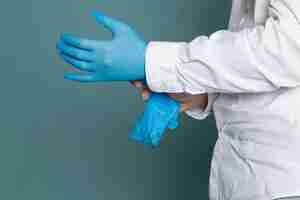 Бесплатное фото Вид спереди человек в белом медицинском костюме и синие перчатки на синем столе