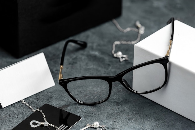 Бесплатное фото Передние оптические очки на сером столе с серебряными браслетами изолировали зрение глазами