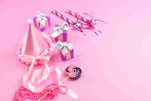 Бесплатное фото Вид спереди фиолетовые подарочные коробки вместе с днем рождения свистит леденец розовая шапка на розовом