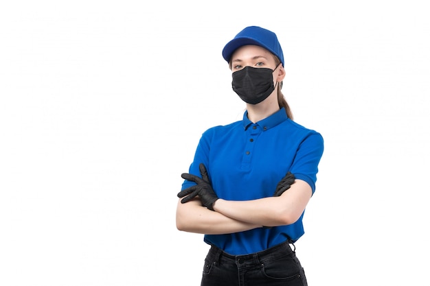 Бесплатное фото Вид спереди молодая женщина-курьер в синей форме, черные перчатки и черная маска позирует
