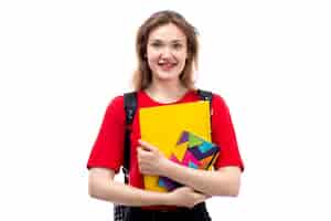 Бесплатное фото Вид спереди молодая студентка в красной рубашке черная сумка, держащая тетради, улыбаясь на белом