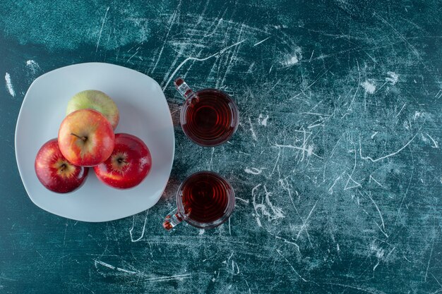 대리석 배경에 접시에 사과 주스와 사과 한 잔.