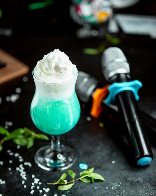Бесплатное фото Стакан экзотического коктейля, украшенный взбитыми сливками в караоке-клубе