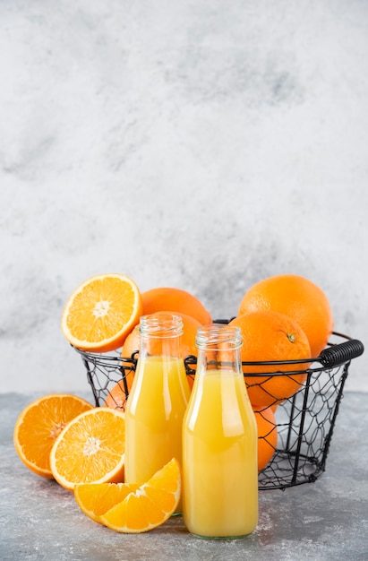 Бесплатное фото Стеклянный кувшин сока со свежими апельсиновыми фруктами на каменном столе.