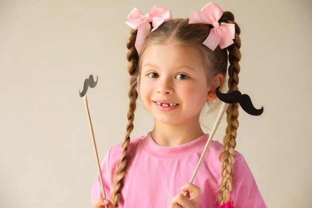 女の子は父の日のために派手な口ひげと帽子を持っています プレミアム写真 女の子は父の日のために派手な口ひげと帽子を持っています プレミアム写真