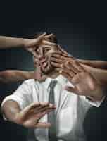 Бесплатное фото Мужчина-модель в окружении рук, как его собственные мысли на темной стене