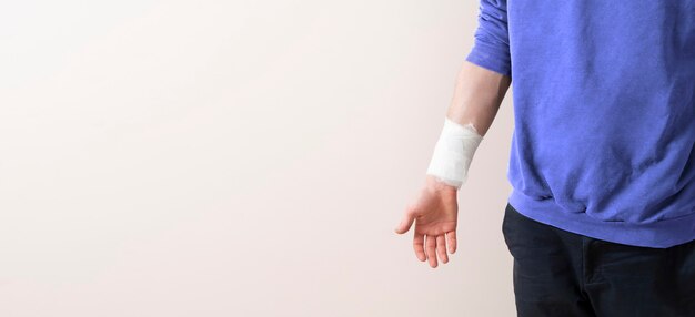 悲しい不幸な男は見下ろし 高さから落ちた後に重傷を負い 長い回復期間にうんざりし 松葉杖で歩こうとし 黄色い壁に向かってポーズをとります 障害のある男性 無料の写真