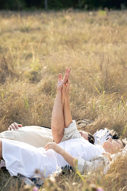 Бесплатное фото Мужчина и женщина держатся за руки, лежа в траве в поле