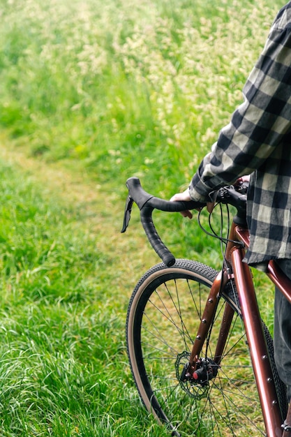 無料写真 男性は自転車のハンドルバーを持ち、森のクローズアップを歩きます