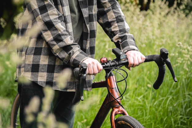 Бесплатное фото Мужчина держит руль велосипеда и гуляет по лесу крупным планом