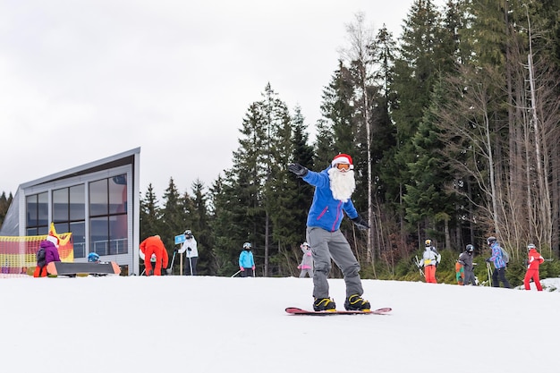 스키장에서 스노보드를 들고 산타 모자를 쓴 남자.