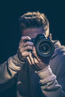 カメラを持った男性写真家が暗闇の中で写真を撮る