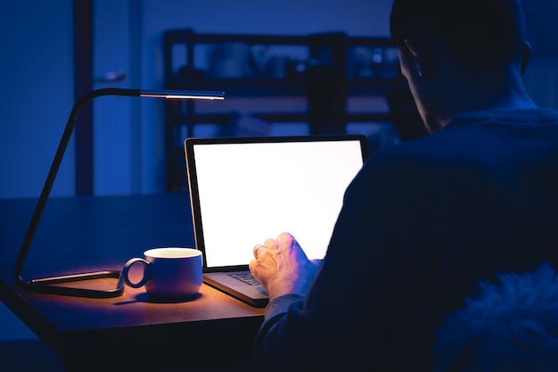 무료 사진 어두운 방에서 일하는 남자가 밤에 노트북을 사용합니다.
