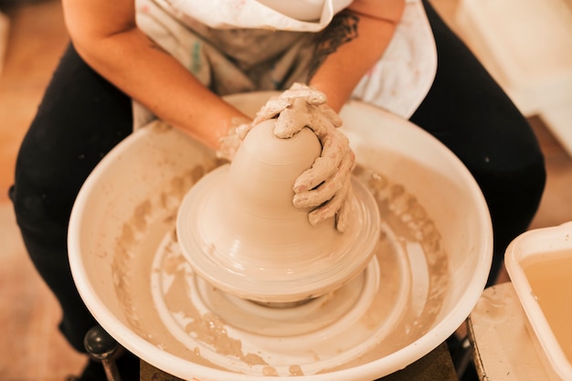 Гончар работает над созданием глиняного горшка на своем гончарном круге