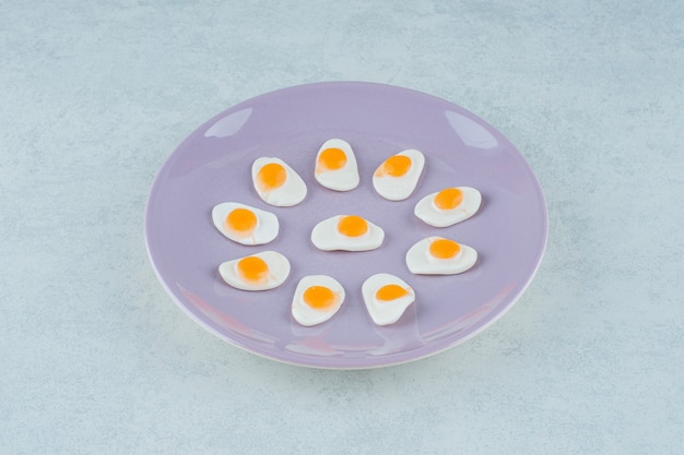 달콤한 젤리 과자의 보라색 접시는 흰색 표면에 계란을 스크램블
