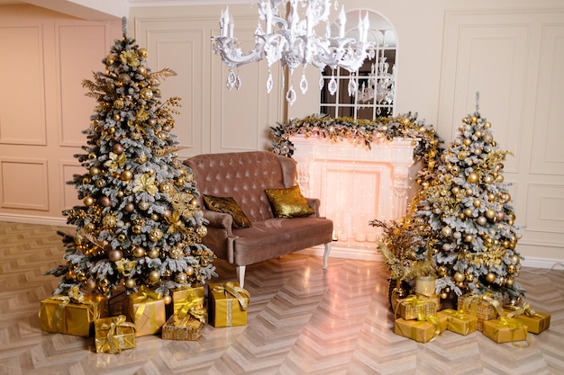 새해 인테리어 디자인의 방, 조명으로 장식 된 크리스마스 트리, 트리 아래 선물, 장난감, 등불, 화환, 실내 벽난로 조명. 축제의 거실. 마법의 새해