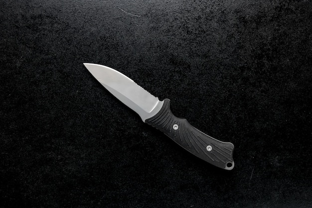 Бесплатное фото Острый небольшой кухонный нож с черной ручкой на черном столе