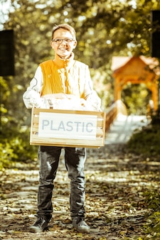 良い​日に​リサイクルする​ために​プラスチック​の​箱​を​持っている​小さな​男の子