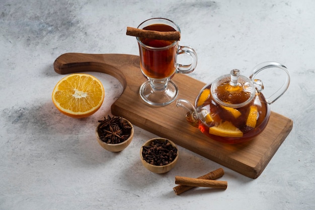 Бесплатное фото Чайник с чаем и долькой апельсина на деревянной доске.