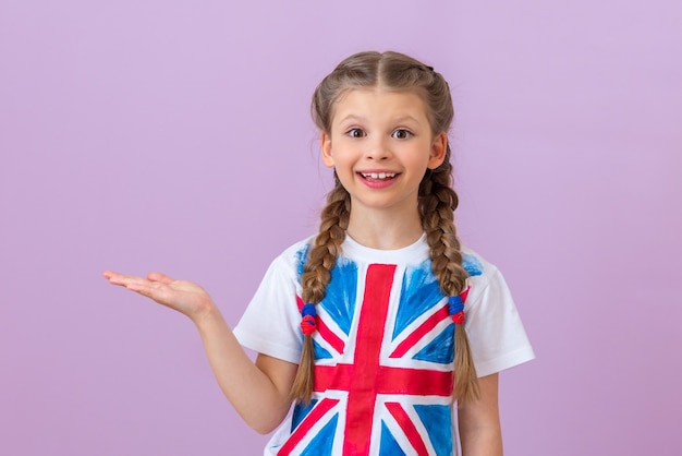 티셔츠에 영국 국기가 그려진 10대 소녀가 손가락으로 옆을 가리키고 있다.