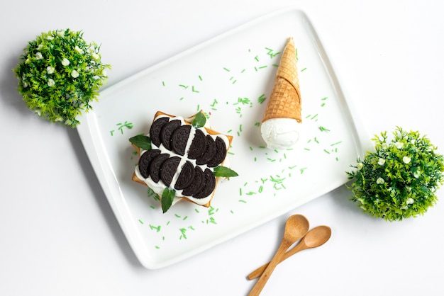 葉​と​白い​背景​の​甘い​夏​の​菓子​の​白い​机​の​中​の​アイスクリーム​で​飾られた​チョコレートビスケットカスタード​と​トップビュークッキーデザート