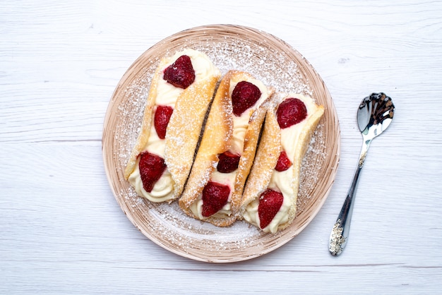 Бесплатное фото Вид сверху вкусные эклеры со сливками и клубникой на белом фоне, фруктовый торт