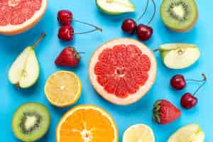 Бесплатное фото Вид сверху свежей красочной фруктовой композиции из спелых и нарезанных фруктов на синем, фруктовом витаминном цвете