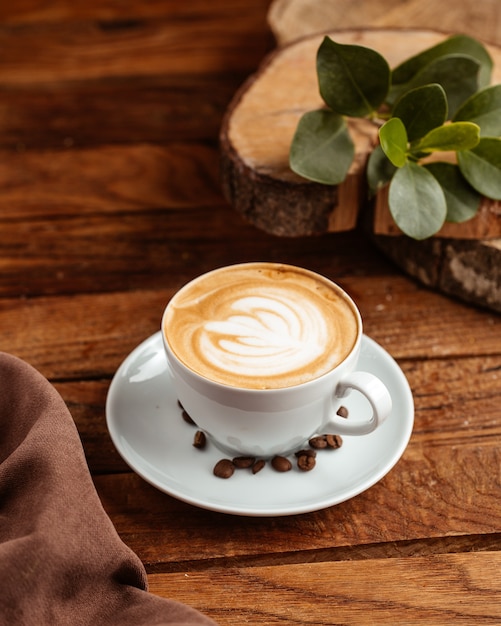 Бесплатное фото Горячий эспрессо с коричневыми кофейными семечками на коричневом деревянном столе, кофейная чашка, вид сверху