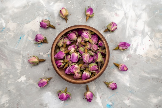 Бесплатное фото Вид сверху фиолетовые цветы внутри круглой миски и выложенные на светлом столе цветное растение цветное фото