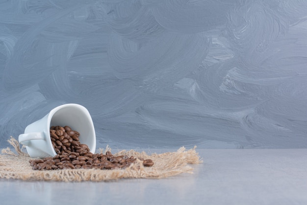 Бесплатное фото Белая чашка жареных кофейных зерен на мраморе.