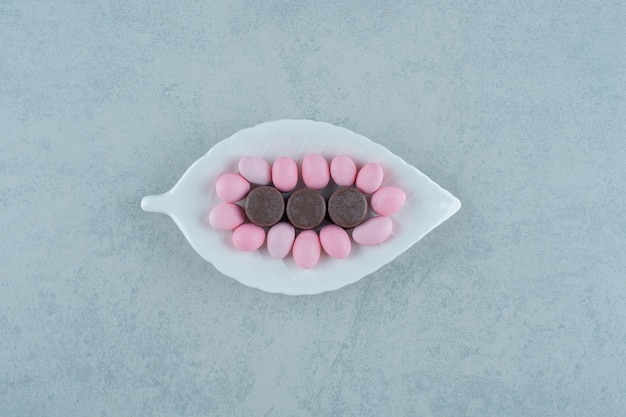 달콤한 분홍색 사탕과 흰색 표면에 초콜릿 쿠키와 흰색 접시