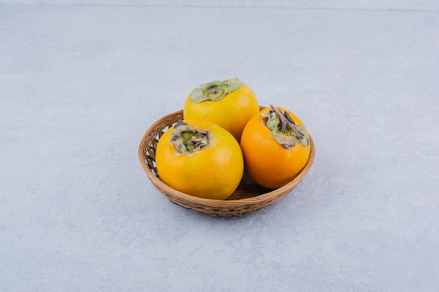 無料写真 白い背景の上の3つの柿の籐のボウル。高品質の写真
