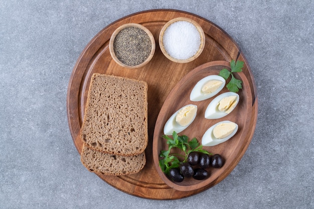 Бесплатное фото Деревянная доска с вареными яйцами и ломтиком хлеба. фото высокого качества