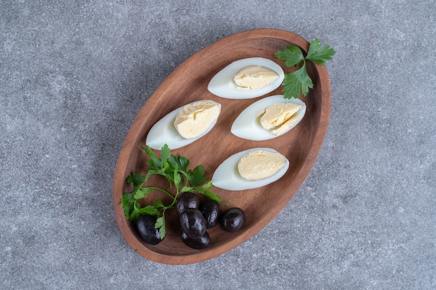Бесплатное фото Деревянная доска с оливками и вареными яйцами. фото высокого качества
