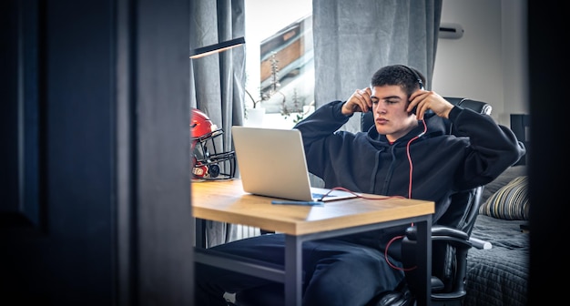 Бесплатное фото Молодой спортсмен сидит перед ноутбуком в своей комнате