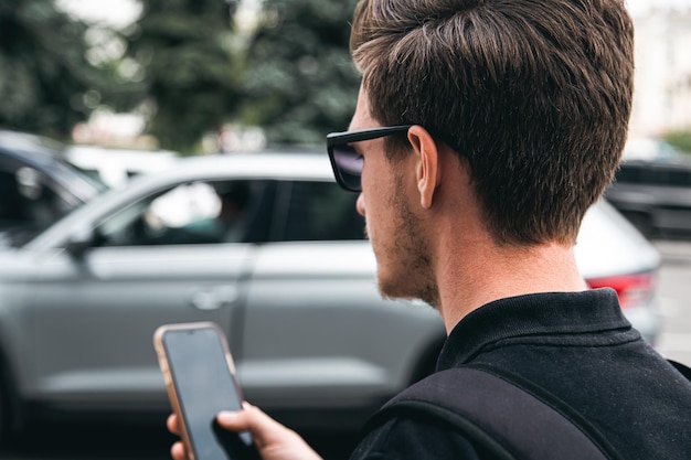 Молодой человек в солнечных очках использует смартфон крупным планом